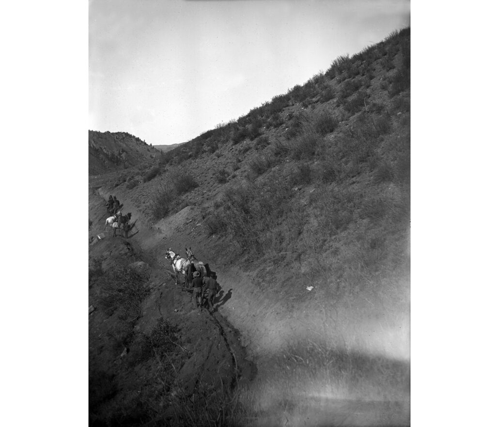 One b/w Glass plate negative and one bw photograph of several men and teams of horses on a hillside. They are working to build the Salvation Ditch. West end of Red Butte is visible in the background. 1903-