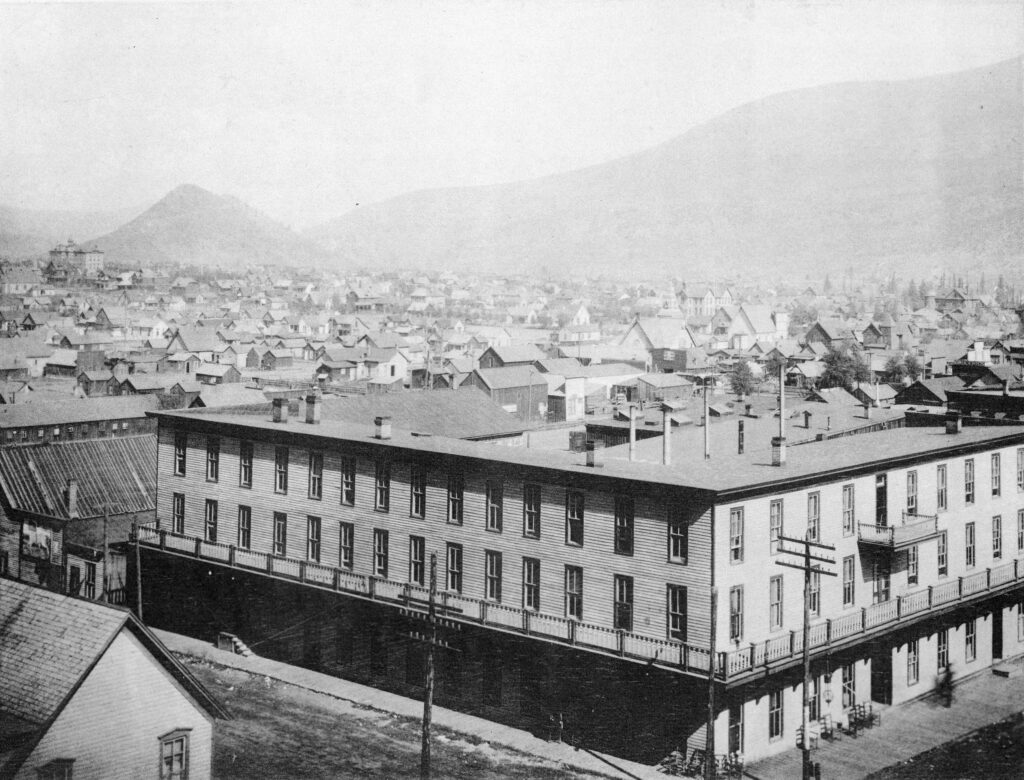 One b/w photograph of the Clarendon Hotel from the Durant Street fire tower looking west. Red Butte is barely visible in the background. The large building to the far left of the image is the Washington School and the Central School is also visible. This image came from "Aspen Illustrated," a booklet sold at Carbary's Corner Bookstore. A caption under the photo in the booklet reads "View looking down the valley from bell tower."
