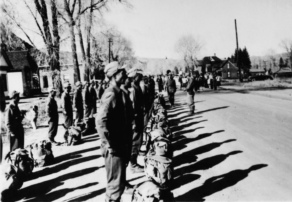 One b/w photograph of an outfit of Tenth Mountain Division soldiers lining up outside of the Hotel Jerome, preparing to leave by truck for Camp Hale, 1943-.