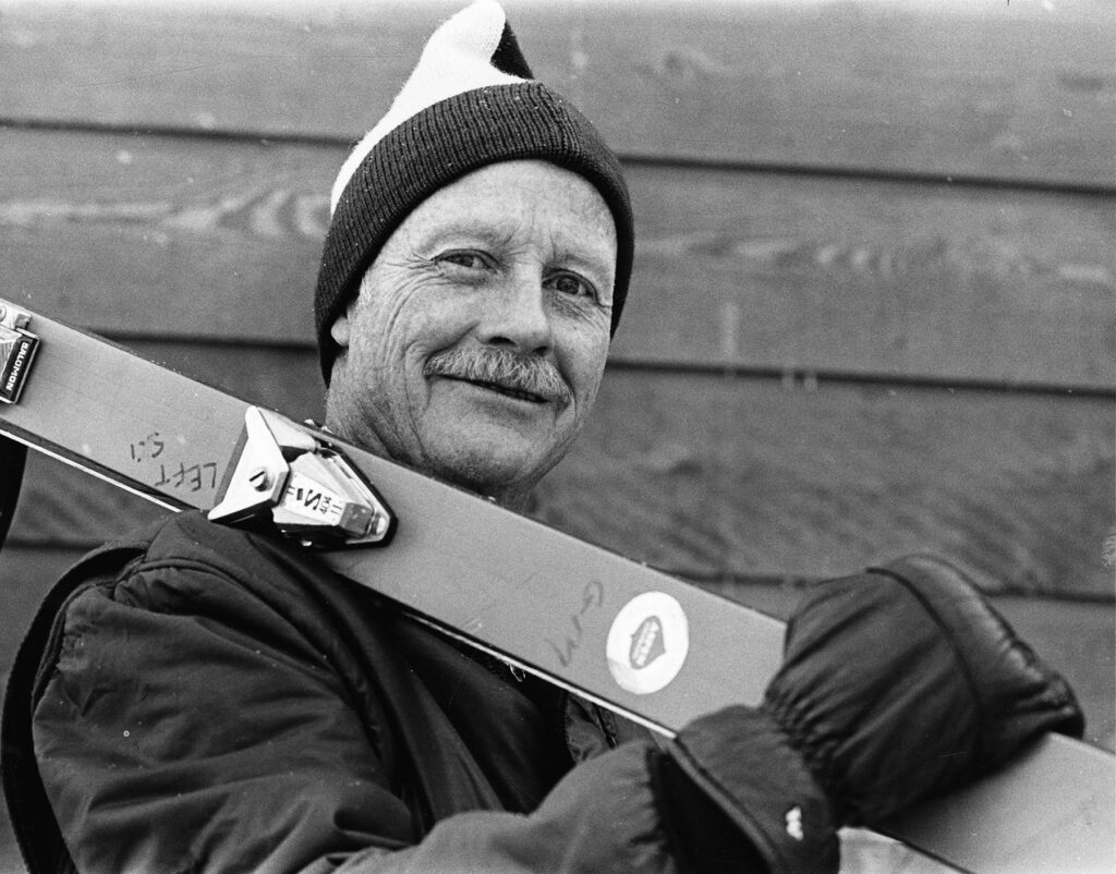 One b/w photograph of D.R.C. Brown, President of the Aspen Skiing Co., with his skis over his shoulder, 1977.