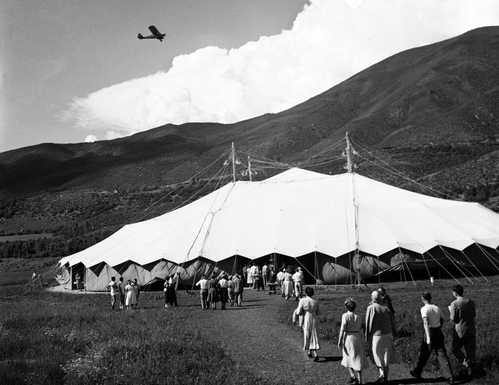 One 2.25" negative and 2.5x2.5" b/w photograph (contact) of attendees entering the Saarinen Music Tent (Saarinen) built for the Goethe Bicentennial Convocation with an airplane flying overhead, circa 1950. The Saarinen tent was used 1949-1964.