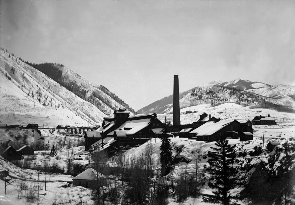 One 5x7 Glass negative of the Holden Lixiviation Works, between 1900 and 1910. Shows the processing plant in the winter with snow. Looking South towards Castle Creek Valley. Can see residential homes on the left side of the image as well as the assay house for the plant on the right which later became the Marolt Ranch home. Castle Creek can be seen in the foreground.