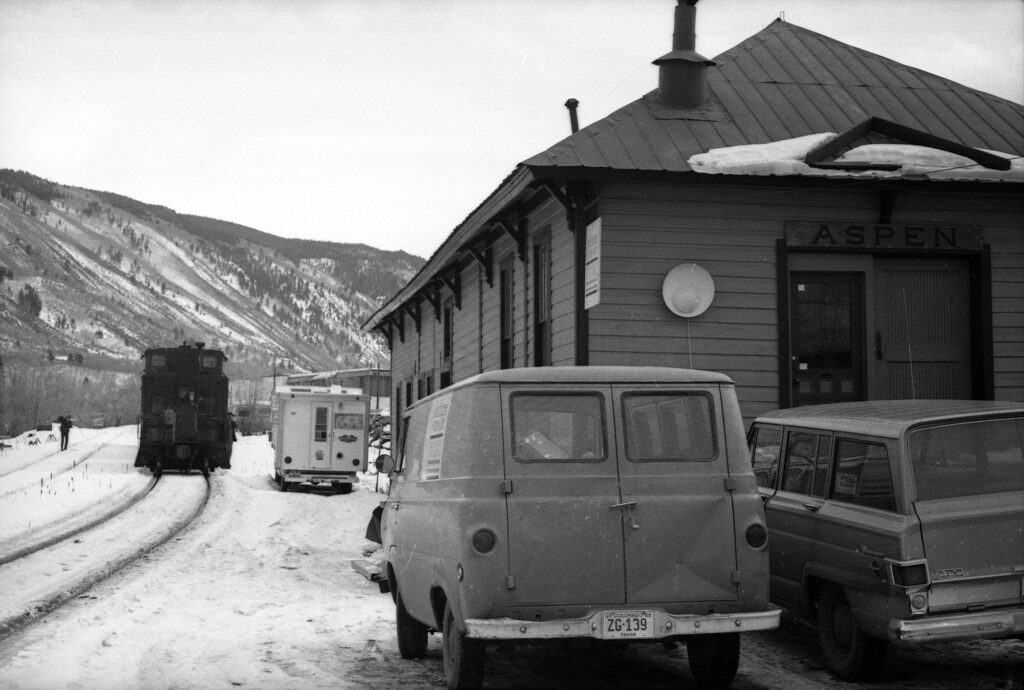 One b/w negative of the last Denver and Rio Grande train to come to Aspen, January 14, 1969. The depot is on the right. Related images are in the Aspen Illustrated News on January 16, 1969 (page 22), with a caption reading "On Oct. 27, 1887 the first train of the Rio Grande Railroad, narrow gauge, puffed into Aspen. On Nov. 5, a dinner for Rio Grande officials was held and a poem written in honor of the occasion, beginning thus: 'Here's to Aspen, her youth and her age; we welcome the railroad and say goodbye to the stage.' On Tuesday, Jan. 14, 1969 the last train of the railroad pulled into Aspen. It is significant that just at this time Aspen is getting its airport control tower. The only time Aspen will again see a locomotive is when the work train comes in this spring to take up the tracks."