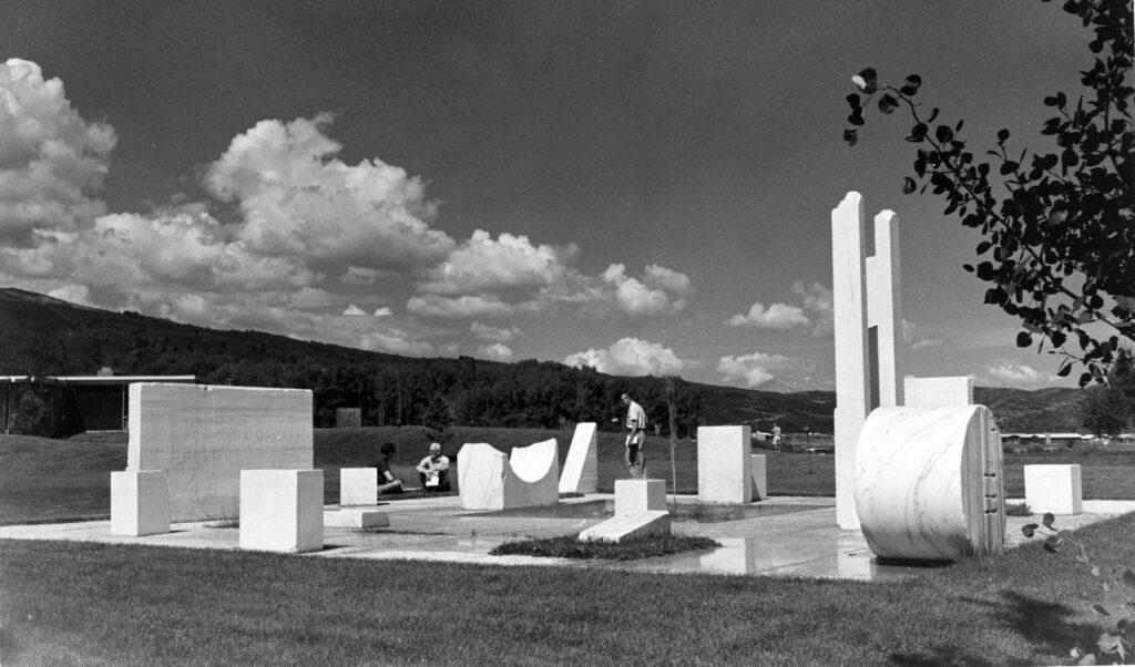 One b/w photograph of Aspen Institute seminar participants relaxing and studying in the Marble Sculpture Garden at the Aspen Meadows. The sculpture garden was designed by Herbert Bayer and installed in 1955.